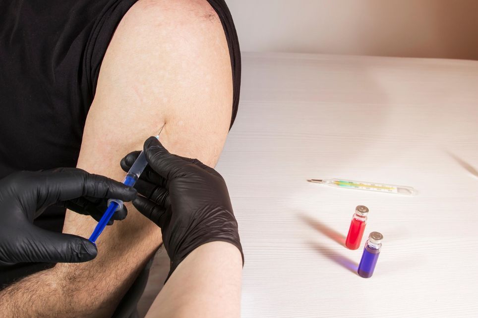 Seseorang menerima suntikan vaksin di lengan atas dalam suasana klinis, simbol perlindungan kesehatan dewasa